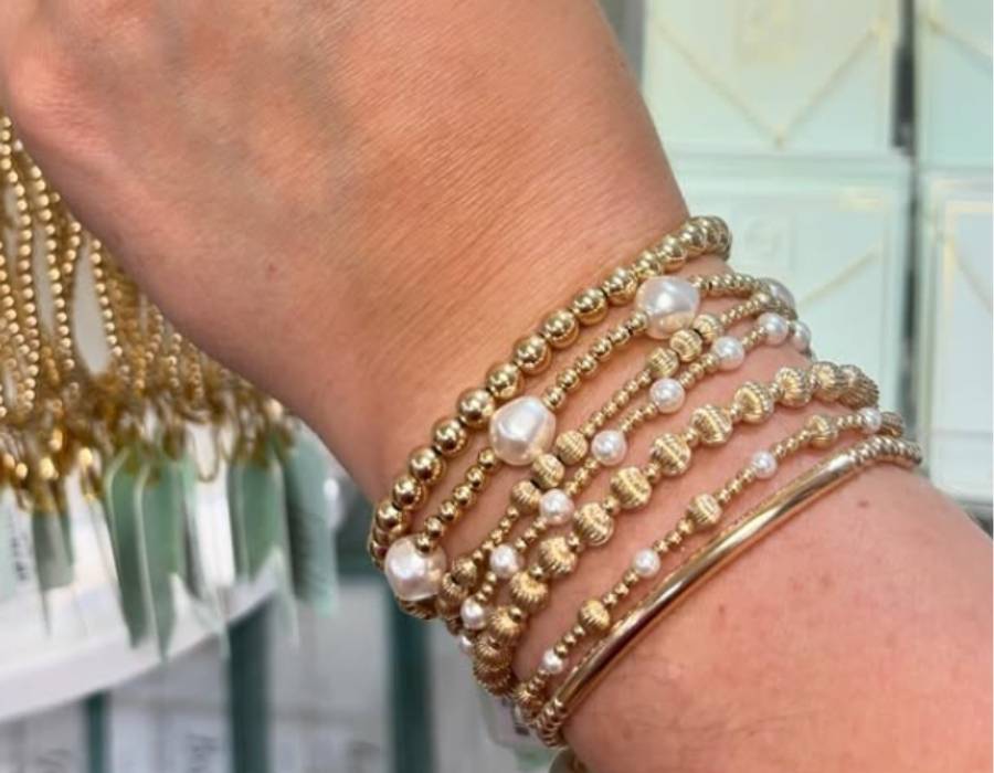 Close-up of a woman's wrist adorned with stacked gold and pearl beaded bracelets, showcasing elegant handmade jewelry from Gifted gift shop in Bluffton, SC.